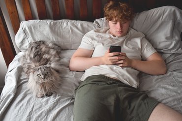Férfi a macskája mellett telefonozik